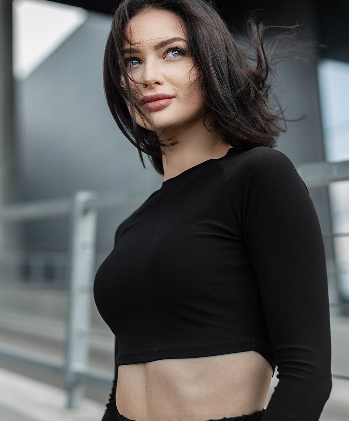 Young woman in cropped black top outdoors.