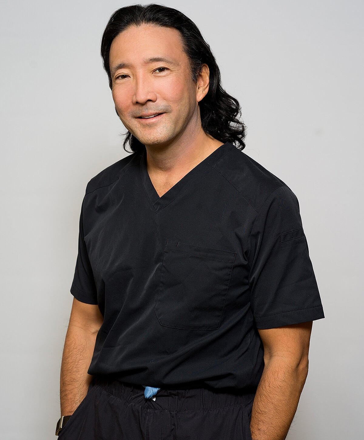 Professional in black scrubs, smiling confidently.