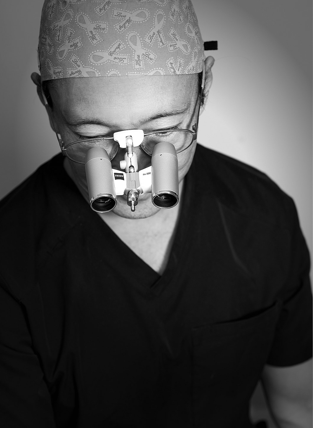 Surgeon wearing magnifying glasses in a surgical setting.