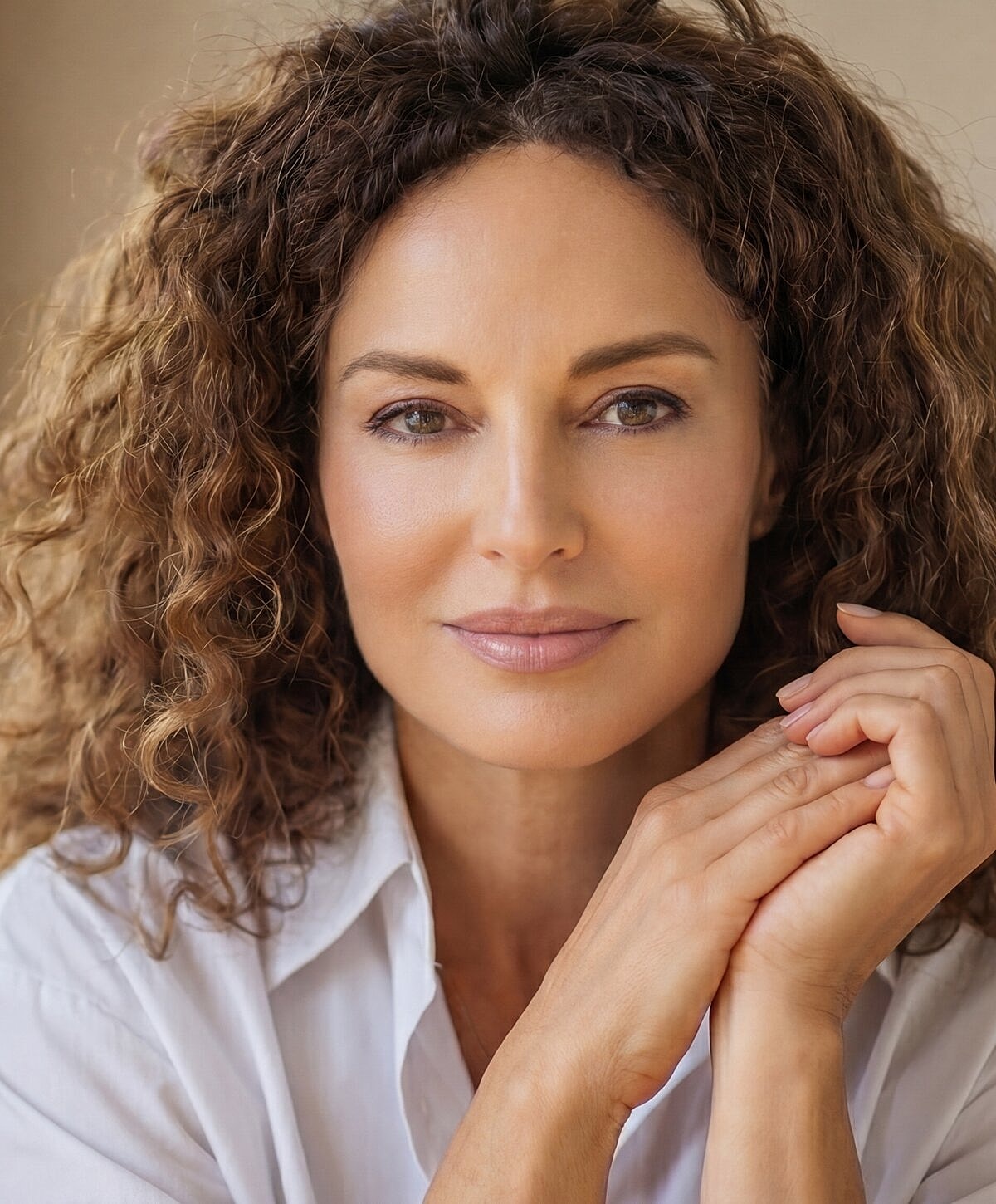 Woman with curly hair, smiling softly at camera.