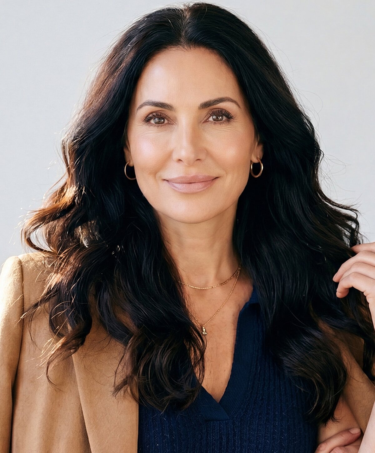 Smiling woman with long dark hair and earrings.