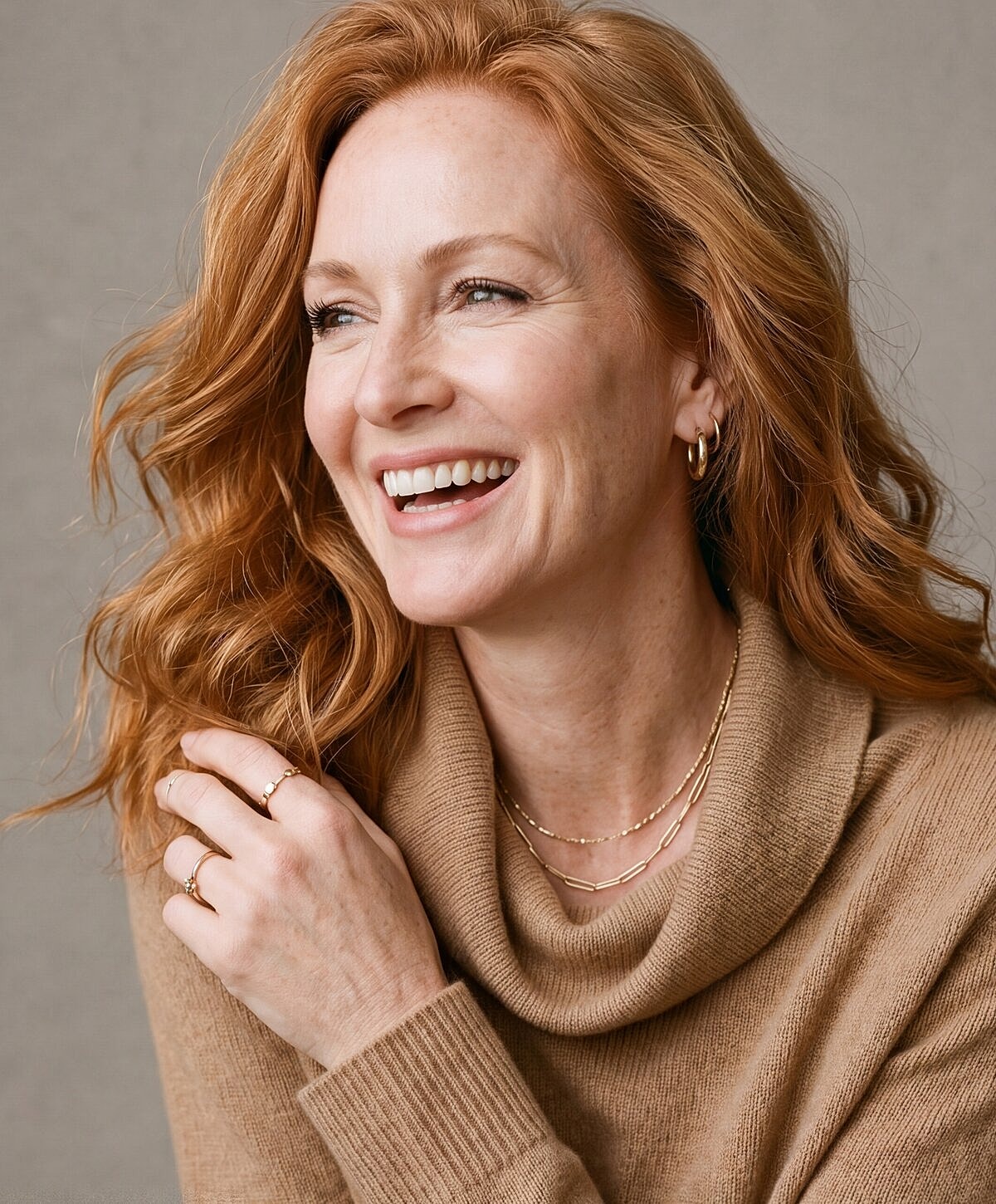 Smiling woman with red hair and cozy sweater.