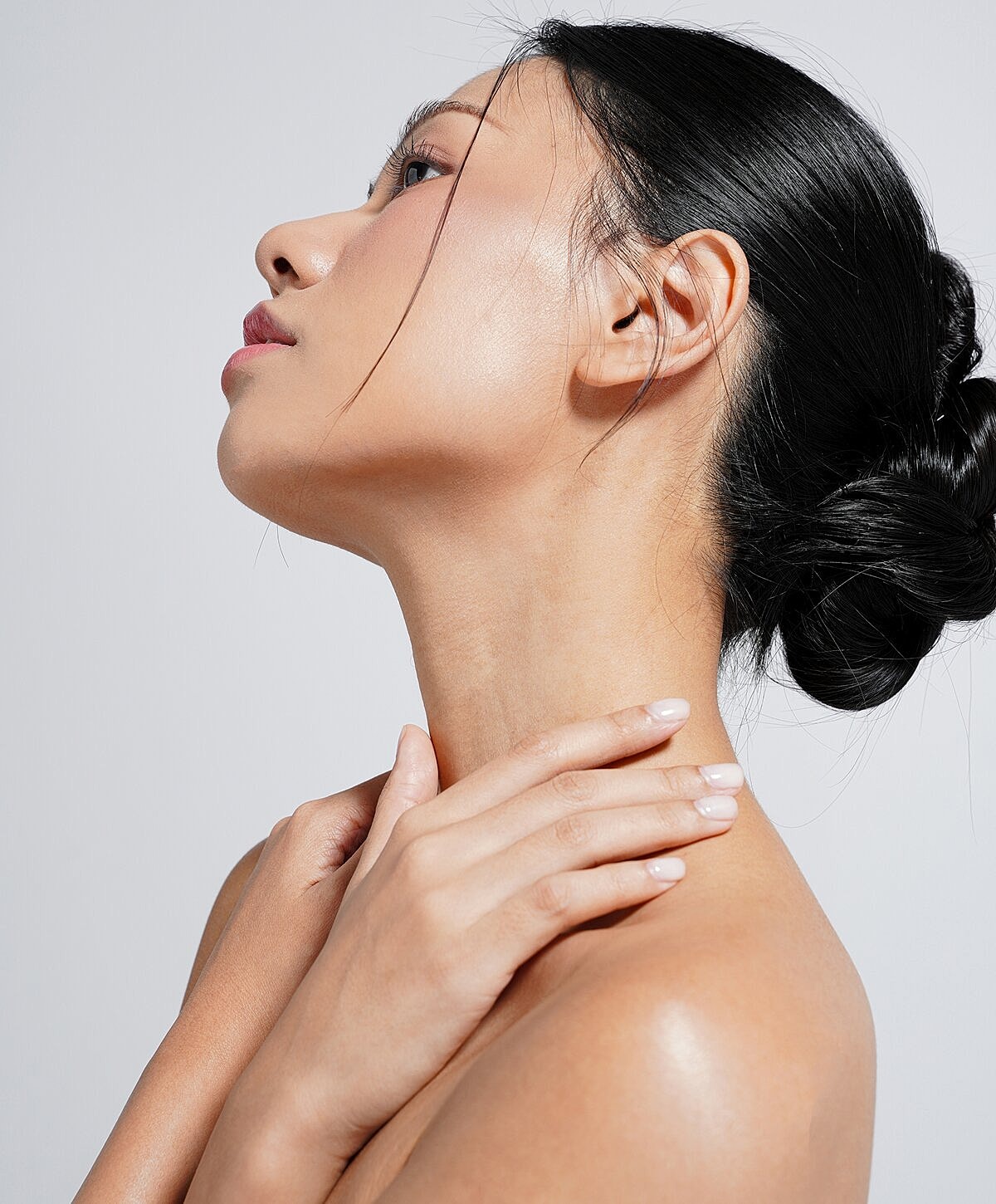 Profile of a woman touching her neck.