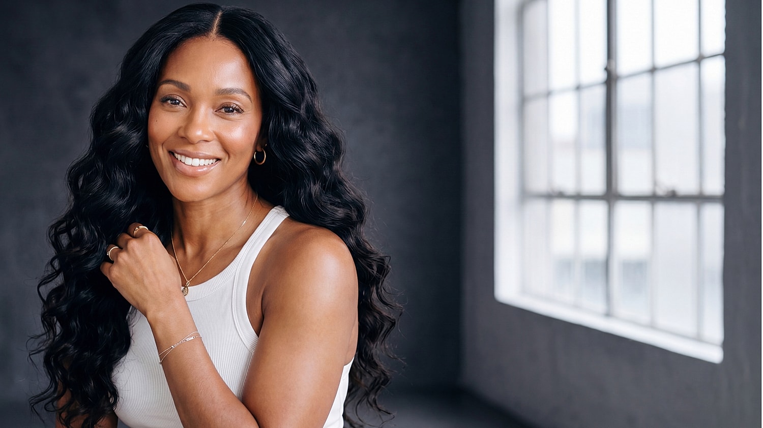 Smiling woman with wavy hair in studio setting.
