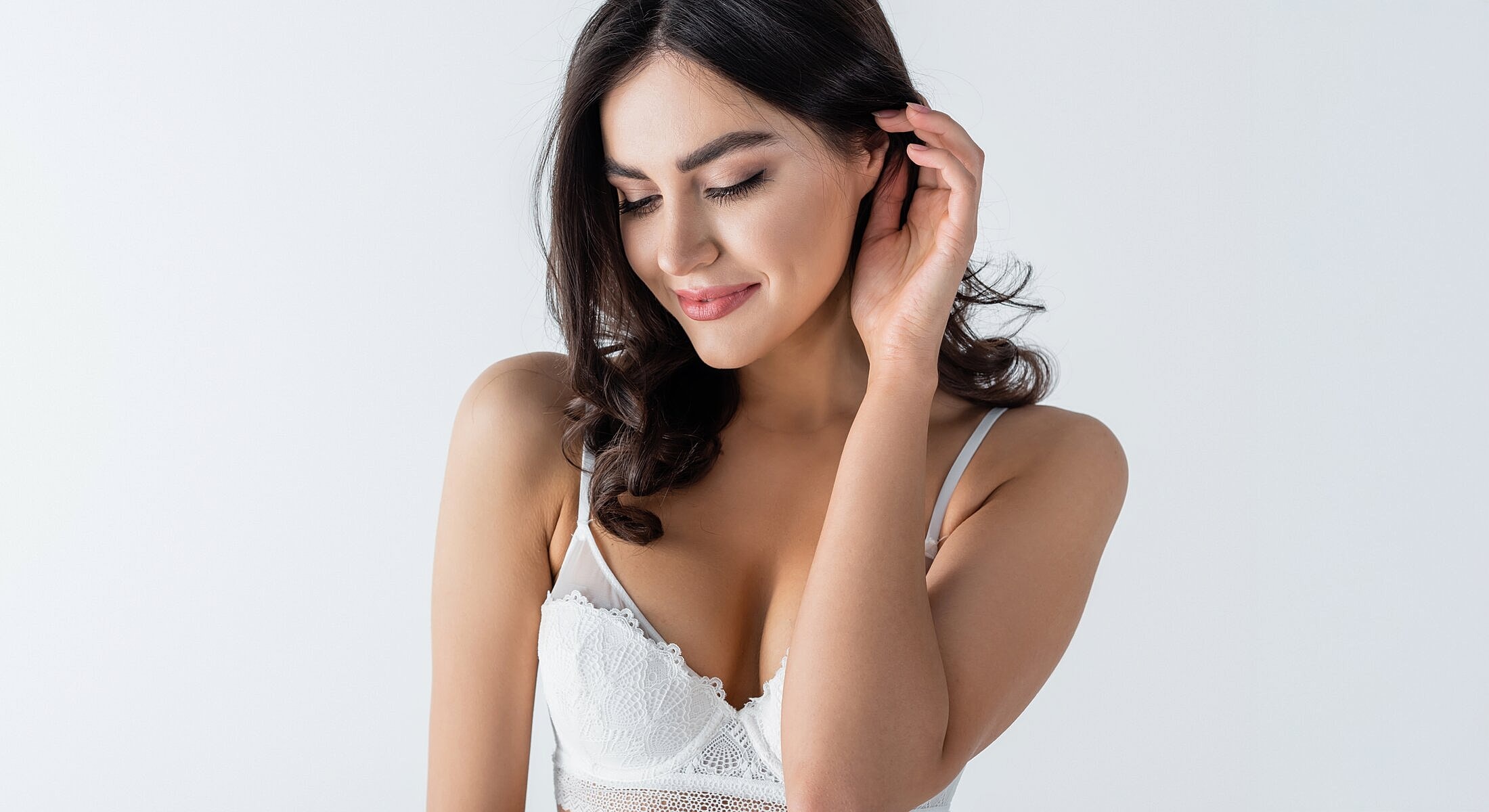 Woman in white lingerie against plain background.