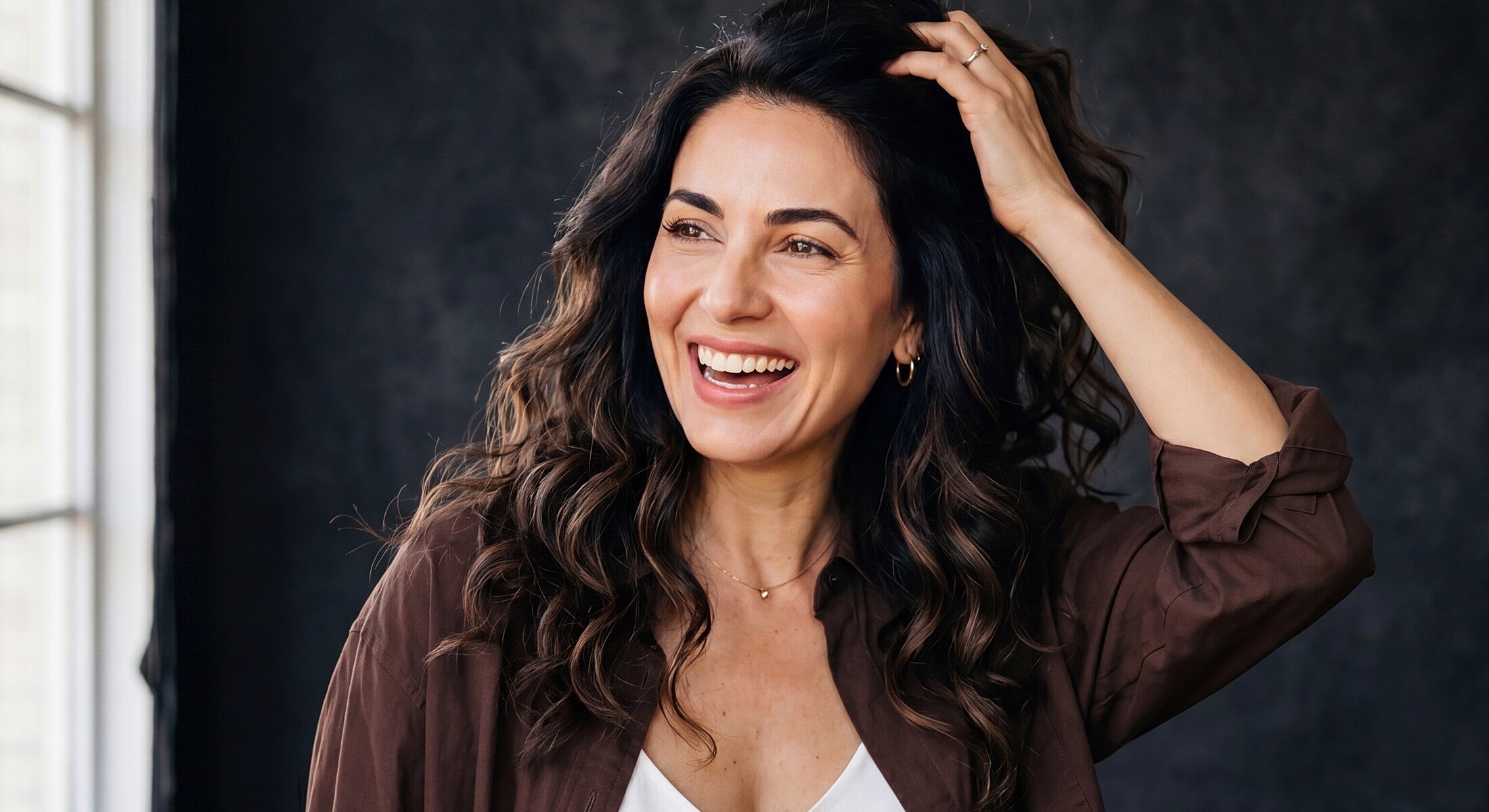 Woman smiling with curly hair against dark background