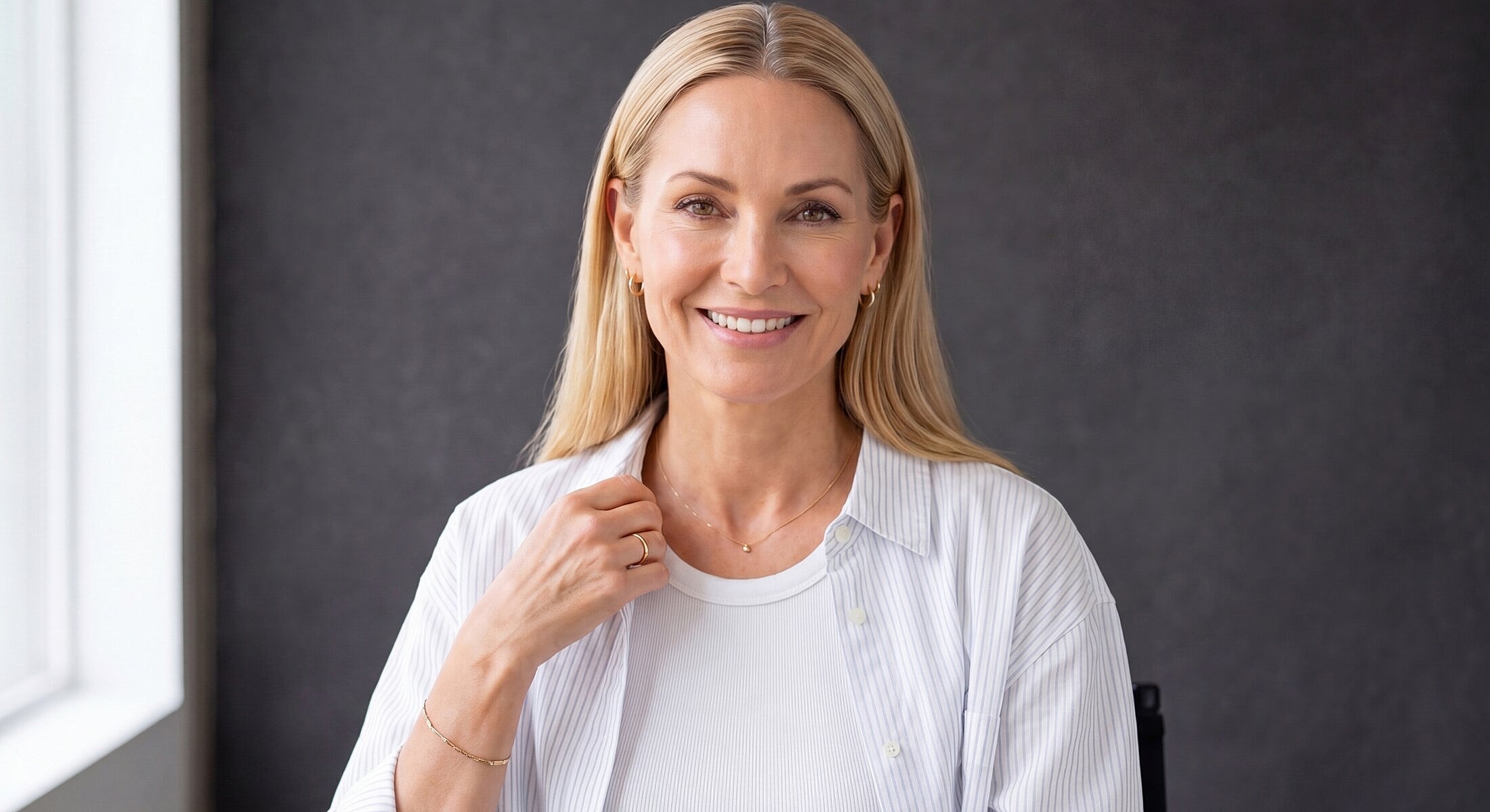 Smiling woman in casual outfit against gray background.