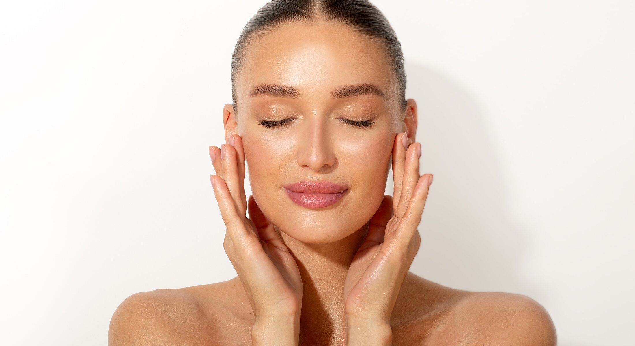 Woman with closed eyes, gently touching her face.